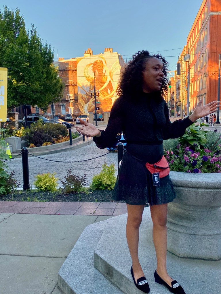 Tour guide standing in front of a mural in Cincinnati